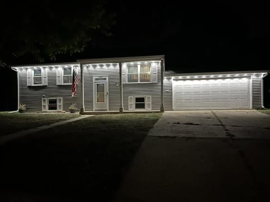 Raised ranch home at night with crisp cool white lighting along the roofline and garage